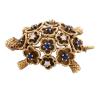 <span class='ref_item'>100 -</span> <span class="object_title">BROCHE EN ORO 18KT, ZAFIROS, RUBÍES Y PIEDRAS INCOLORAS</span>  <p><span class="technical_description">Broche con forma de tortuga realizado en oro de 18kt. En el caparazón tallas de zafiros con peso total aprox 0.70ct y piedras incoloras. Detalles en ojos de rubíes con un peso total 0.06ct<br/>Cierre: Aguja con mecanismo de seguridad<br/>Medidas: 4,5 x2,5cm</span><br>Peso: <span class="PESO_HCES1">21</span> <span class="PESOUMED_HCES1">gr.</span><br></p>